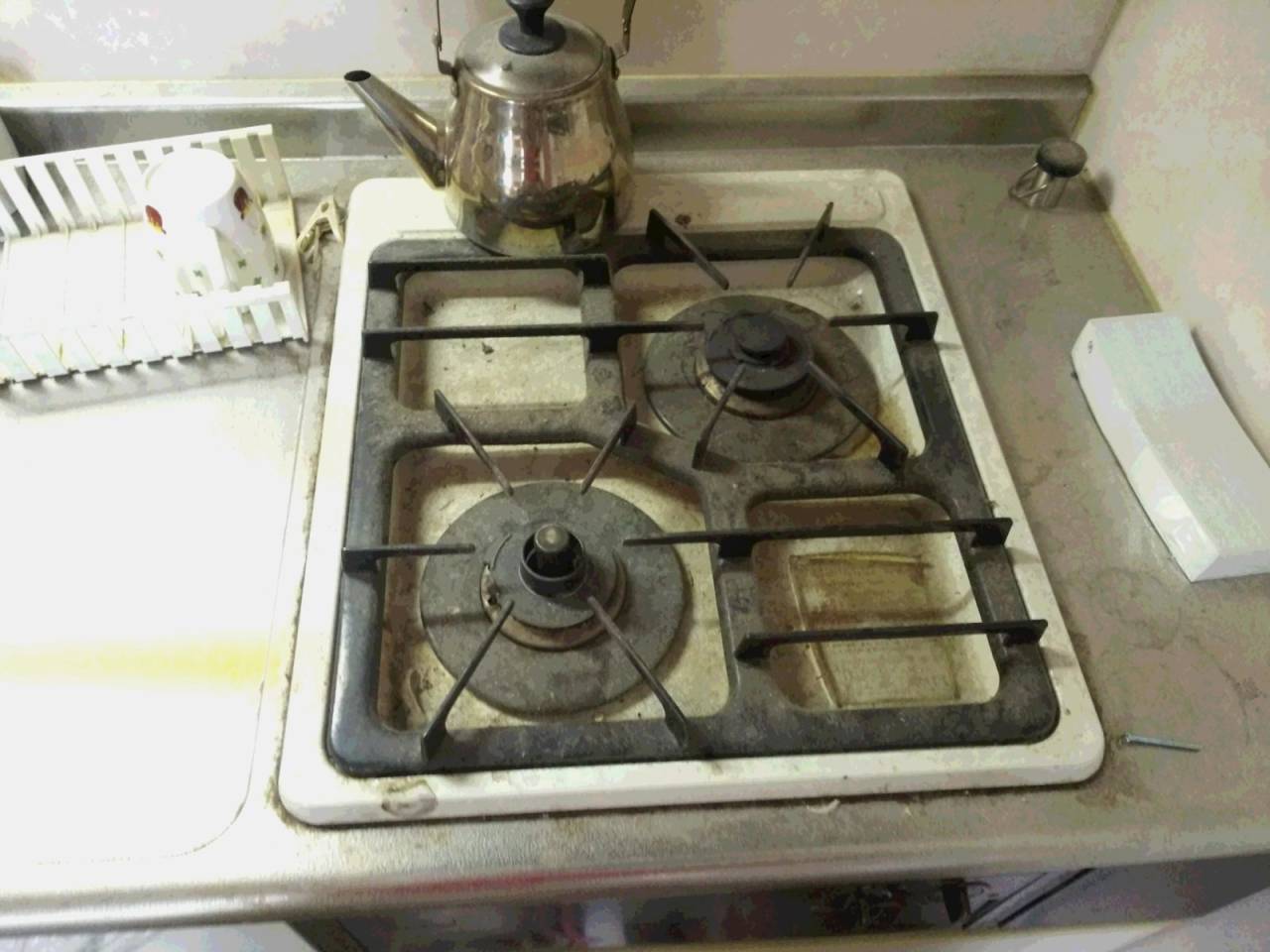 清掃前<br>ワンルームマンションのミニキッチンのガス台、油・汚れでベトベトです。